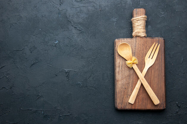 刀顶视图交叉木汤匙和叉子上的木制服务板上的黑色桌子复制的地方棍子勺子木头