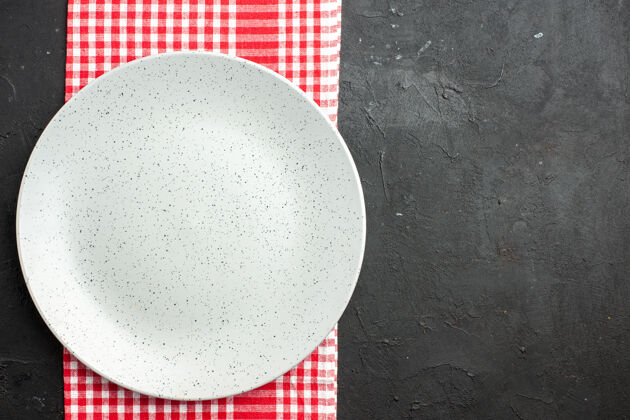 白色顶视图白色圆板上的红色和白色方格餐巾上的黑色桌子与副本的地方圆形玻璃白色圆形盘子