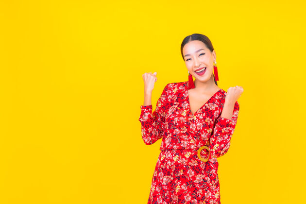 手表美丽的亚洲年轻女子在彩色墙上的中国新年概念中的微笑东方人旗袍文化