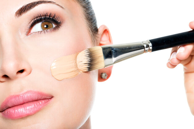 治疗化妆师在女人脸上涂上液体色调的粉底容颜女性女性