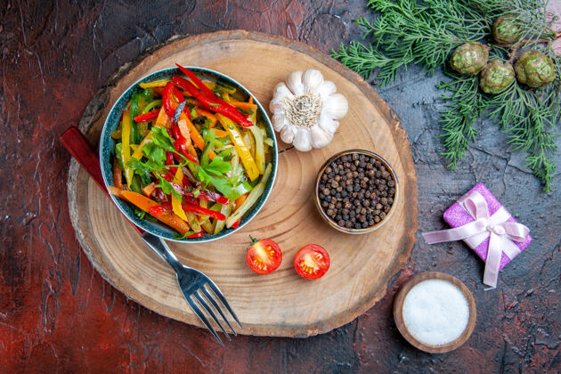午餐顶视图蔬菜沙拉在碗叉大蒜黑胡椒在乡村板冷杉枝在暗红色的桌子上餐盘菜肴蔬菜