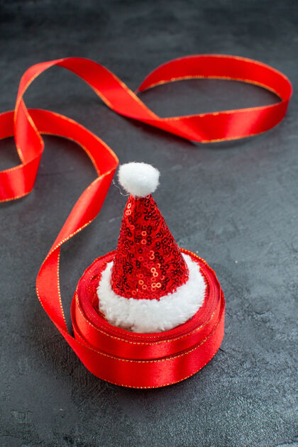 壁板垂直视图上的圣诞老人帽子的一卷丝带上的右侧黑暗的背景弓用具容器