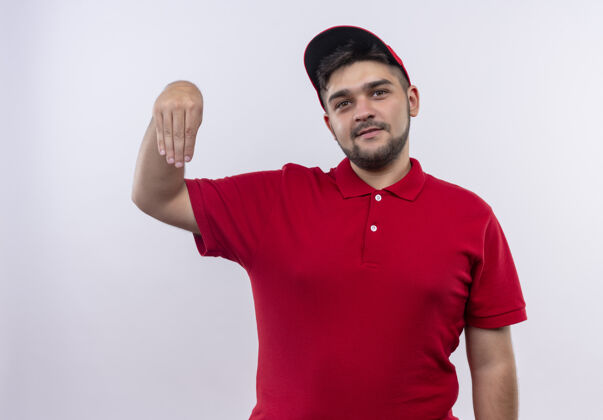 看年轻的送货员穿着红色制服 戴着帽子 自信地用手做手势 肢体语言概念交货年轻身体