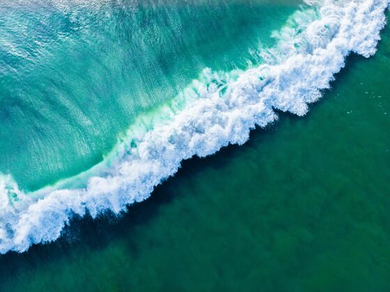 岩石空中拍摄的蓝色波浪海-完美的背景云干燥海岸线