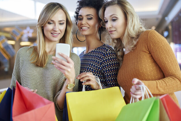 交谈购物时用手机的女孩商场客户无线互联网