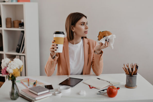 欢呼女企业家在办公室吃午餐的画像工人在工作场所吃汉堡包工人年轻女性