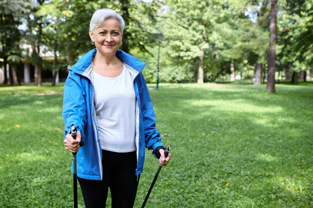 远足快乐精力充沛活跃的女性退休人员在蓝色夹克享受北欧散步使用特别设计的杆 呼吸新鲜空气户外体育活动 健康的生活方式 人和衰老新鲜年龄老人
