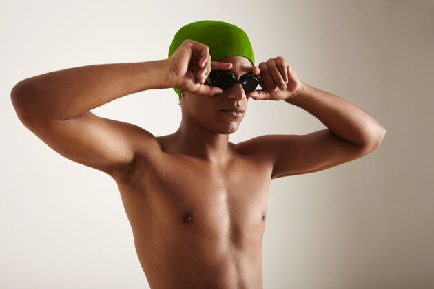 铁人三项年轻健康放松的黑色游泳运动员戴着绿色的帽子戴上黑色的护目镜锻炼健身专业