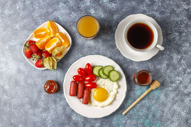美味早餐盘子里有鸡尾酒香肠 煎蛋 樱桃番茄 糖果 水果和一杯桃子汁咖啡早餐蛋黄
