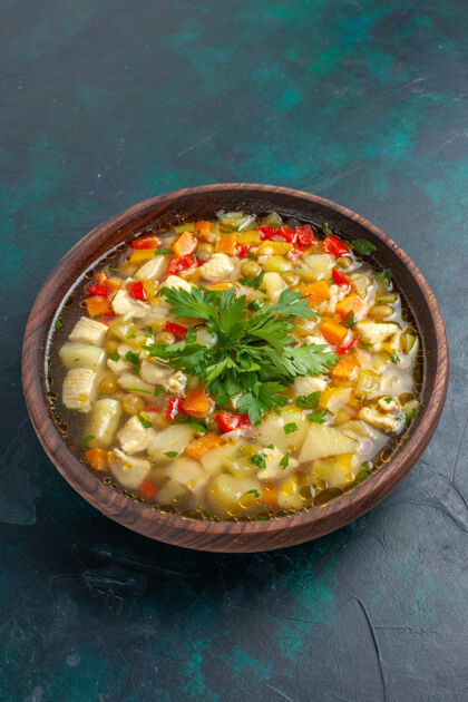 汤在深色桌子上的棕色盘子里 可以看到美味的蔬菜汤 里面有不同的配料里面美味配料