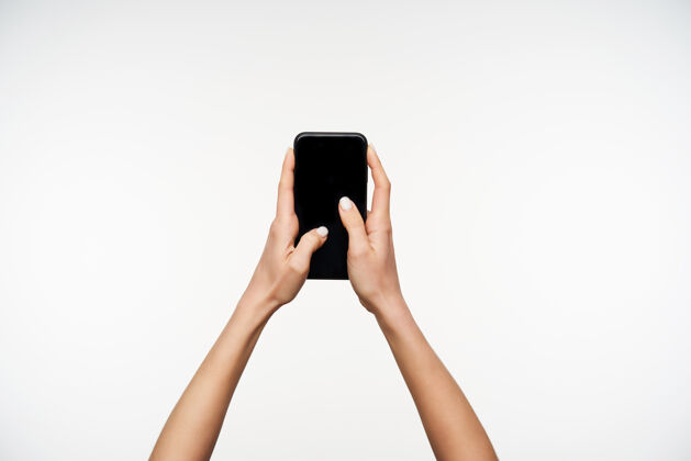 信号年轻的白皙漂亮的手拿着黑色的现代智能手机 在白色的屏幕上摆姿势 拇指保持在屏幕上的肖像黑色姿势女士