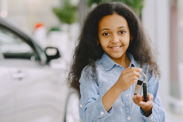快乐快乐的 漂亮的小女孩 拿着车钥匙 展示它 微笑着摆姿势孩子人美丽