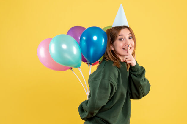 年轻正面图年轻的女性藏在背后的彩色气球气球五颜六色聚会