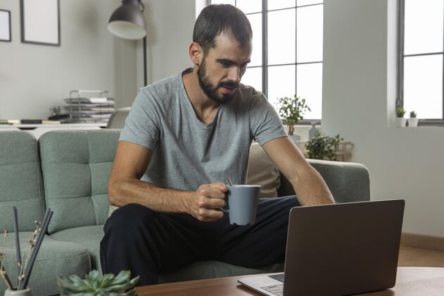 男人喝咖啡在家用笔记本电脑工作的男人工作远程工作职业