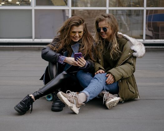 乐趣带着智能手机的女性朋友一起在户外玩娱乐朋友横向