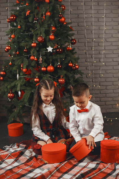 快乐孩子们坐在圣诞树旁孩子们打开装有礼物的盒子玩具室内毛衣