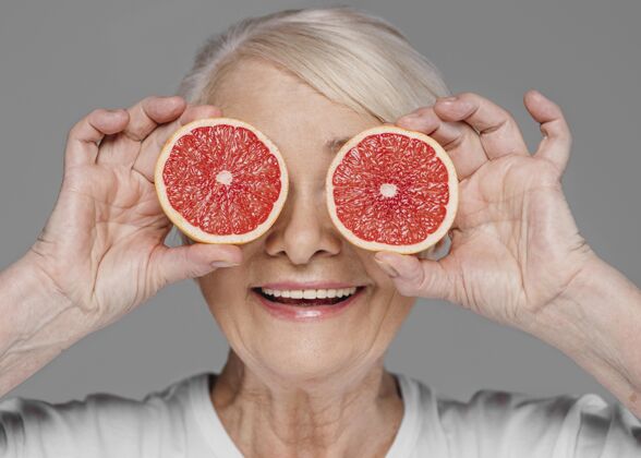 老年人特写拿着红橙子片的女人成人自我护理护理