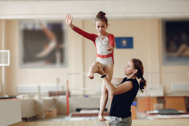 酒吧儿童体操平衡木女子体操运动员在体操比赛中练习单杠带着孩子的教练艺术孩子女孩