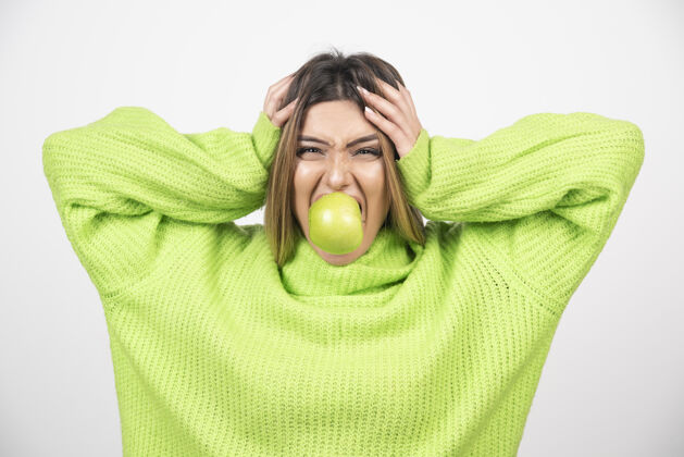 吃穿着绿色t恤的年轻女子正在吃苹果营养年轻食物