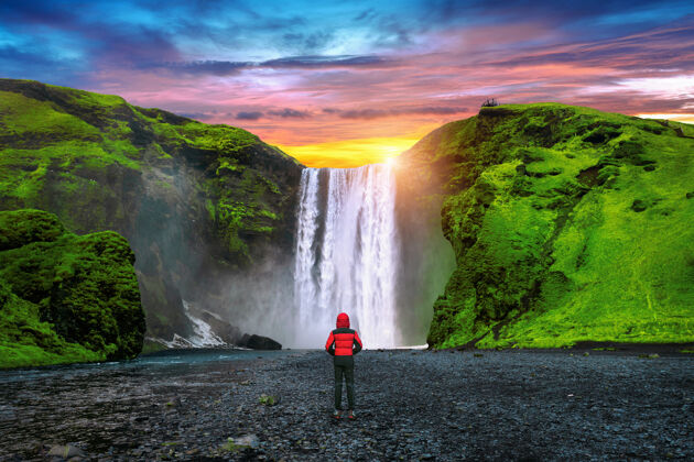 风景冰岛的斯科加福斯瀑布穿红色夹克的家伙看着斯科加福斯瀑布前面悬崖自然