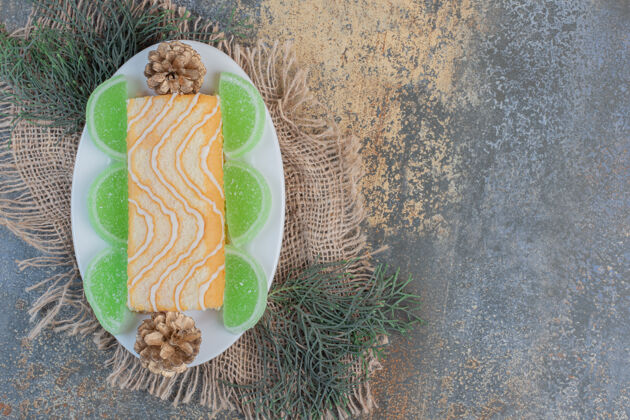 甜点白色盘子上有绿色果酱和松果的甜卷高质量的照片果冻糖果果酱