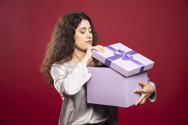 惊喜年轻女子正在检查紫色礼盒礼物年轻生日
