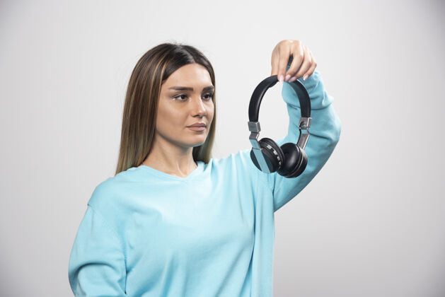音乐穿着蓝色运动衫的金发女孩拿着耳机 准备戴上耳机听音乐金发女年轻