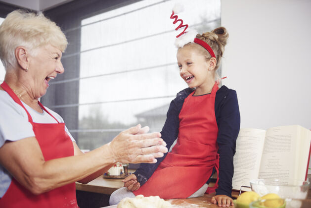 玩奶奶和女孩在厨房里玩做蛋糕烹饪向下