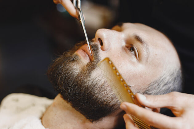 顾客有胡子的男人有客户的理发师有梳子和剪刀的男人椅子胡子客户