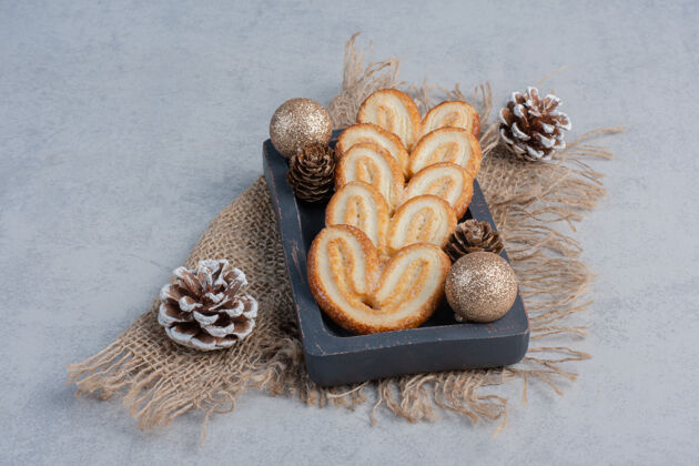 美味薄饼和圣诞装饰品放在大理石表面的小托盘上甜点甜点糖