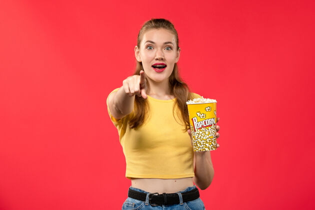 成人正面图年轻女性在电影院拿着爆米花在红墙电影院看女性欢乐时光电影电影电影院年轻女性