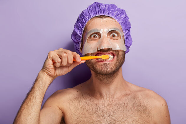 新鲜快乐男人早上刷牙 敷美容面膜 戴淋浴帽的特写镜头健康刷牙姿势