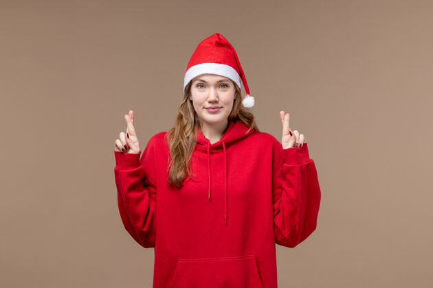 圣诞节前视图圣诞节女孩交叉她的棕色背景节日模型圣诞节手指漂亮圣诞女孩视图