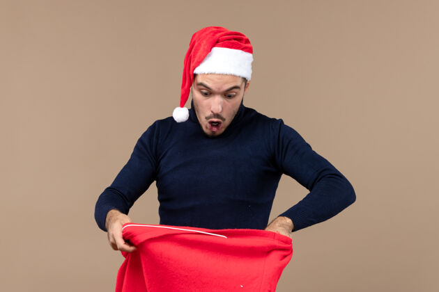 工作室前视图年轻男性检查棕色背景圣诞老人礼物袋礼物棕色休闲