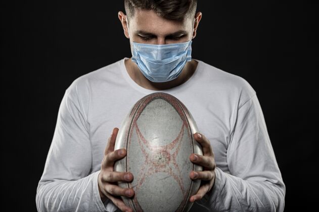橄榄球联盟男橄榄球运动员戴着医用面罩拿着球活动球员男子