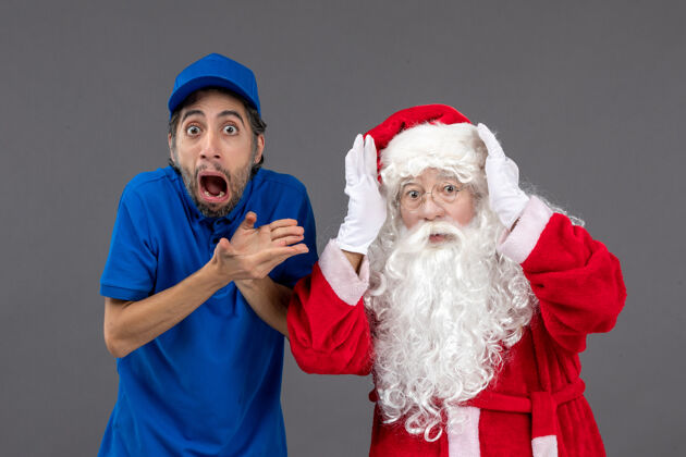 节日灰色墙上的圣诞老人和男信使的正面图人圣诞庆祝
