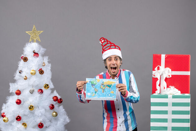 无辜前视图惊讶的男子与螺旋弹簧圣诞帽举行地图附近的白色圣诞树和复制空间举行春天礼物