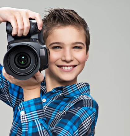 摄影师男孩拿着相机拍照高加索男孩的肖像 手里拿着数码相机图片单反摄影
