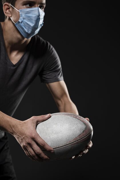 完全接触手持医用面罩的男性橄榄球运动员侧视图锦标赛运动员橄榄球联盟