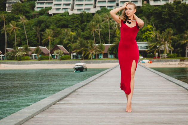 风年轻漂亮迷人的女人独自站在豪华度假酒店的码头上 暑假 红色长裙 金色头发 性感服装 热带沙滩 诱惑 性感 微笑赤脚身体表情