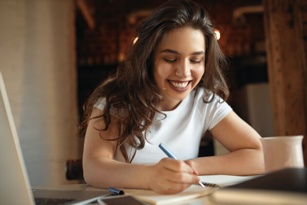 青少年美丽的女学生 胖乎乎的脸颊 拿着笔迹在笔记本上 而学习远离家书桌互联网文书工作