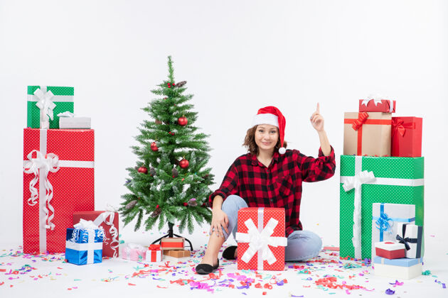 人年轻女子围坐在圣诞礼物和白色墙上的小圣诞树前的视图小快乐女人