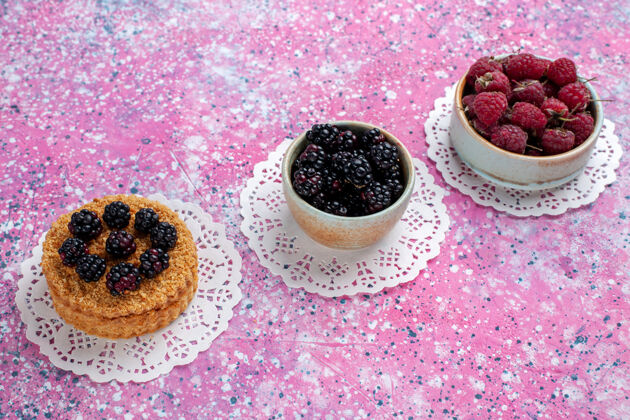 棕色半顶视图小黑莓蛋糕与覆盆子和新鲜黑莓淡粉红色的背景浆果黑莓小