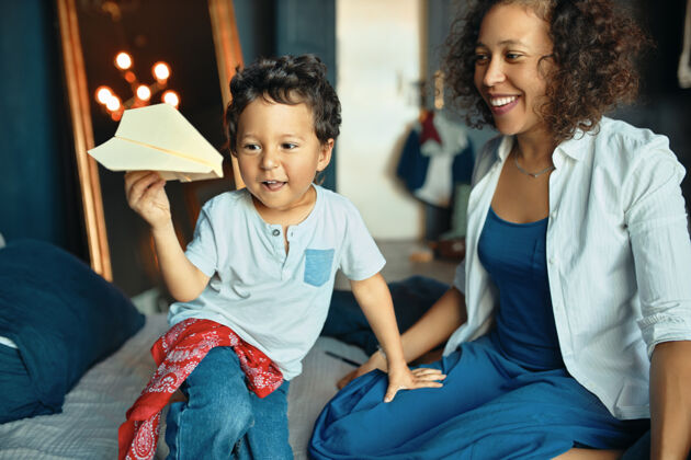 可爱人 童年 父母和家庭生活的概念快乐的年轻混血女和她的可爱的小儿子在家里玩的肖像折纸家庭母亲