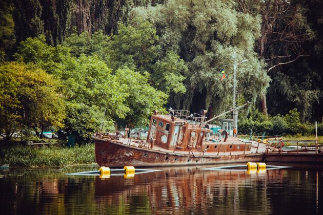 平静一艘古老的木船在湖边 四周是郁郁葱葱的大自然反射景观海洋