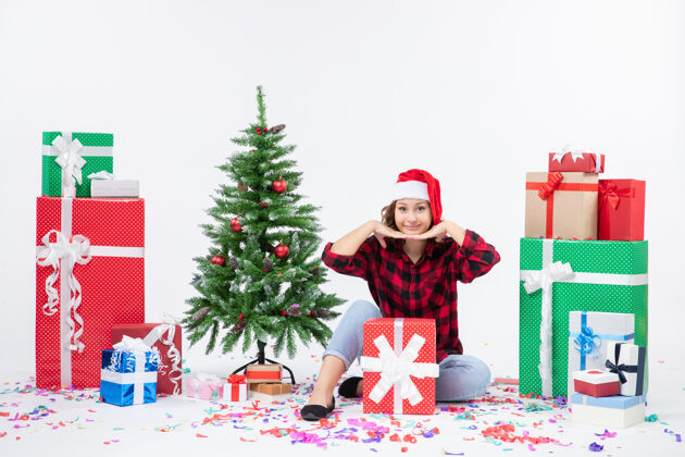 礼物年轻女子围坐在礼物和白色墙上的小圣诞树前的视图礼物人节日