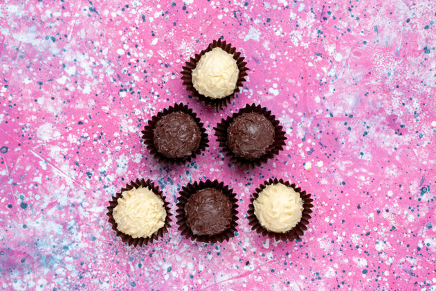 粉红顶视图美味的巧克力糖果白色和黑色巧克力粉红色背景邦邦糖美味