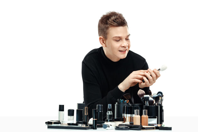 粉剂专业化妆师与工具隔离在白色工作室的背景下男性在女性profesion性别平等的概念开朗沙龙年轻