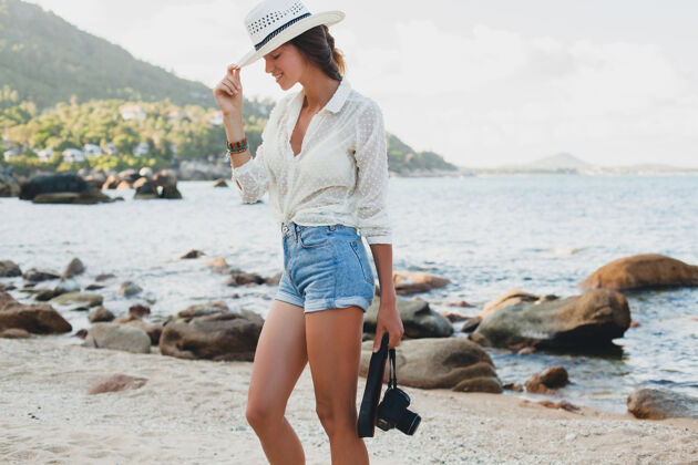 年轻在亚洲度暑假的年轻漂亮的时髦女人 在热带海滩上放松 数码相机 随意的波西米亚风格 海洋风景 苗条的棕褐色身体 独自旅行相机女性户外
