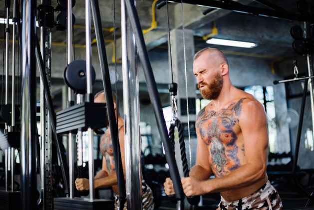 工作纹身的健康男人在健身房锻炼运动向上拉肌肉